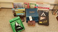 Photo showing a collection of board games, puzzles, and a green electric putting cup device arranged on a carpeted floor.