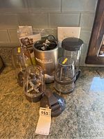 Photo showing Nutribullet base unit, power cord, multiple blending cups with blades, and lid on countertop