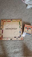 Square vintage Monopoly game board with classic property squares and central 'MONOPOLY' text. Board shows signs of wear and age.