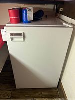 Front view of white mini fridge with Autoscold brand label, closed door, some items on top.