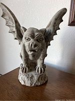 Front view of winged gargoyle statue on wood surface