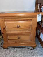 Front view of the wooden nightstand showing two drawers with round wooden knobs and the light natural wood finish.