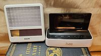 Two devices: Philips goLITE light therapy device and Ivee alarm clock on a book
