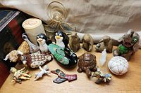 Wide shot of assorted figurines and ornaments laid out including glass angels, penguins, wooden birds, and ceramic dishes.