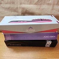 Stacked boxed hair styling tools showing boxes labeled Sutra and Jos Eber brands.