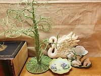 Green wire tree ornament with swan wall decor, bunny cup, and floral plates in background