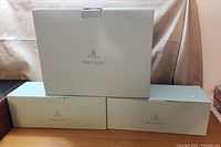 Three boxed PartyLite candle holders with white packaging stacked on a table.