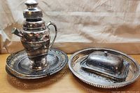 Photo showing all items in the lot together on wooden surface: large tray, smaller tray with covered butter dish, and coffee pot.