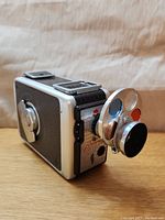 Side view of vintage Kodak Brownie 8mm movie camera with attachable lens showing body and film advance knob