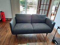 Front view of the two-seat gray upholstered couch showing cushions and armrests.
