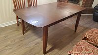 Wood dining table with center leaf removed showing two end sections, strong wood grain, and angle tapered legs