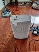 White Hysure T8PLUS humidifier unit placed on a wooden floor with cables nearby. Front and top buttons visible.