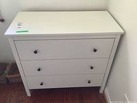 Front view of the white IKEA dresser showing three drawers and black knobs.