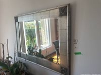 Full view of the framed mirror hanging on the wall with natural light reflecting from windows.