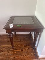 Full view of the occasional table showing wood frame, glass top and turned legs