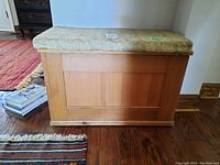 Storage bench showing wood base with paneling detail and upholstered top.