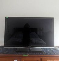 Front view of Samsung 46-inch LCD TV, powered off, showing the flat screen and stand on a surface.
