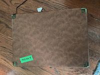 Closed view of the Victrola portable record player case showing brown leatherette with metal corner protections and measurements sticker