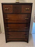 Front view of four-drawer wooden dresser with brass handles and dark wood finish.