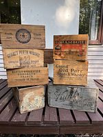Front and top view showing stacked wooden liquor and wine crates with visible vintage branding from Drambuie, Grand Old Parr, Gloag's Perth Whisky, Barton & Guestier, KWV, and The Kuntz Brewery.