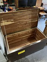 Open view showing cedar lining inside the wooden hope chest, lid held open by side support rods.