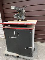 Full view of the Craftsman radial arm saw mounted on a black cabinet with wheels, showing the front and side of the setup.