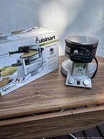 Cuisinart appliance with original box on wooden surface, showing front and side with control panel and logo.