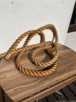 Photo of a thick, heavy twisted rope coiled on a wooden surface, showing its natural fiber texture and consistent twist pattern.