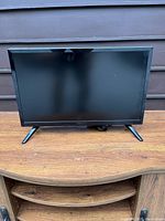Front view of a 21-inch Insignia TV with black frame and dual-leg stand on wooden surface.