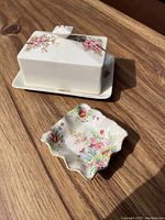Photo showing the James Kent Apple Blossom ceramic cheese or butter dish with fitted lid decorated with pink apple blossom motif alongside a small floral decorative dish with scalloped edges.