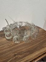 Clear view of glass punch bowl, 12 matching glass cups arranged around it, and a clear glass ladle on side on wood table.