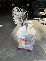 Propane heater mounted on white propane cylinder with wheeled base, showing tank and side view of heater.