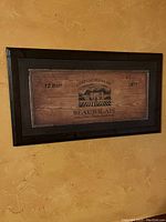Wooden wine sign with 'Chateau Pierre Beaujolais' text and branding framed on textured wall background.