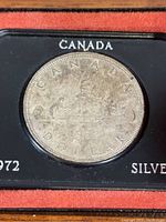 Front side of 1962 Canadian silver dollar coin showing the Voyageur design in its display case.
