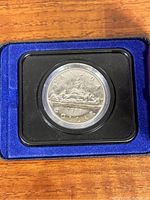 Front side of the 1975 Canadian silver dollar coin showing a sailboat design with 'CANADA', 'DOLLAR', and '1975' markings in original display case with blue velvet lining.