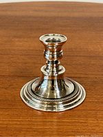 Full view of antique silver plate candlestick showing overall shape, design, and polished surface.