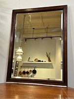 Front view of antique wooden framed mirror showing beveled glass and dark wood frame.