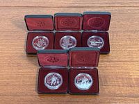 Five Canadian commemorative silver dollar proof coins in original black boxes with red velvet lining and protective capsules.