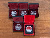 Five Canadian proof silver dollar coins displayed in original black presentation boxes with red velvet interiors and protective covers.