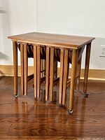 Rectangular main table with four round tables nested beneath, side view showing casters and leg design