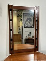 Full front view of vertical walnut framed mirror with textured tile panels on sides.