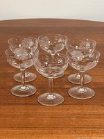 Set of 6 vintage etched cornflower stemware glasses arranged on wooden table.