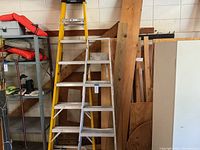 Two ladders side by side against a garage wall, shelving and wooden boards in the background. Shows size and condition.