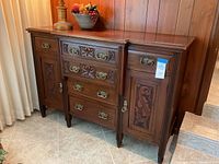 Full view of antique wooden buffet sideboard showing carved central drawers and side cabinet doors with brass handles.