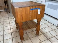 Front-left angled view showing end-grain butcher block top, turned legs, and slatted bottom shelf