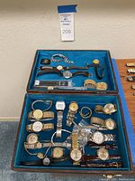 Two-tier wooden tray lined in blue felt showing top and bottom compartments of lot contents