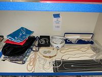Wide view of jewelry including pearl necklaces, silver chains, and multiple fabric jewelry bags
