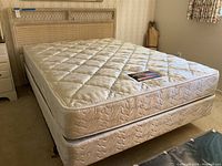 Overall queen bed setup with wicker headboard, mattress and box spring in guest bedroom, from side angle.