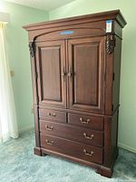 Front view of the full Thomasville armoire showing the two door cabinet above three full-width drawers and ornate crown molding on top.