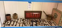 Wide view of assortment of skeleton keys displayed on table with wooden cigar box and brass mortar.